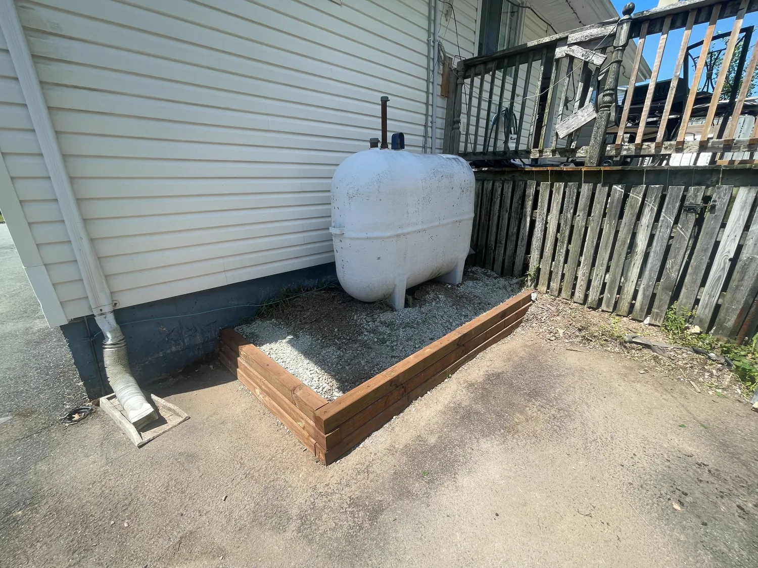 After: timber enclosure and clean gravel base around outdoor oil tank